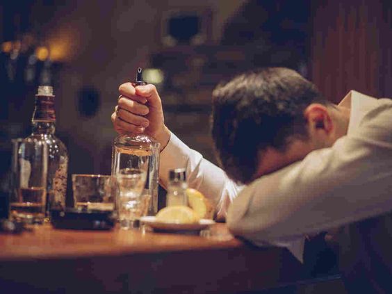Man showing signs of alcohol addiction at a bar, a common symptom of Alcohol Use Disorder needing treatment in Nagpur